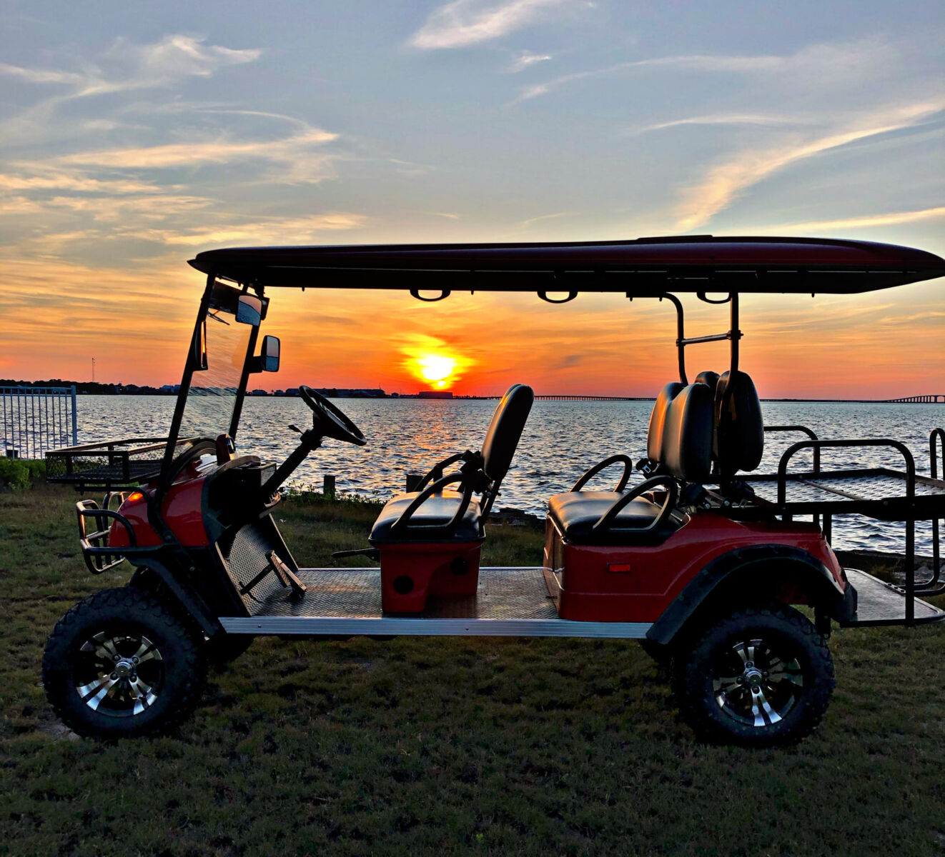 A golf cart in front of a water-front sunset.