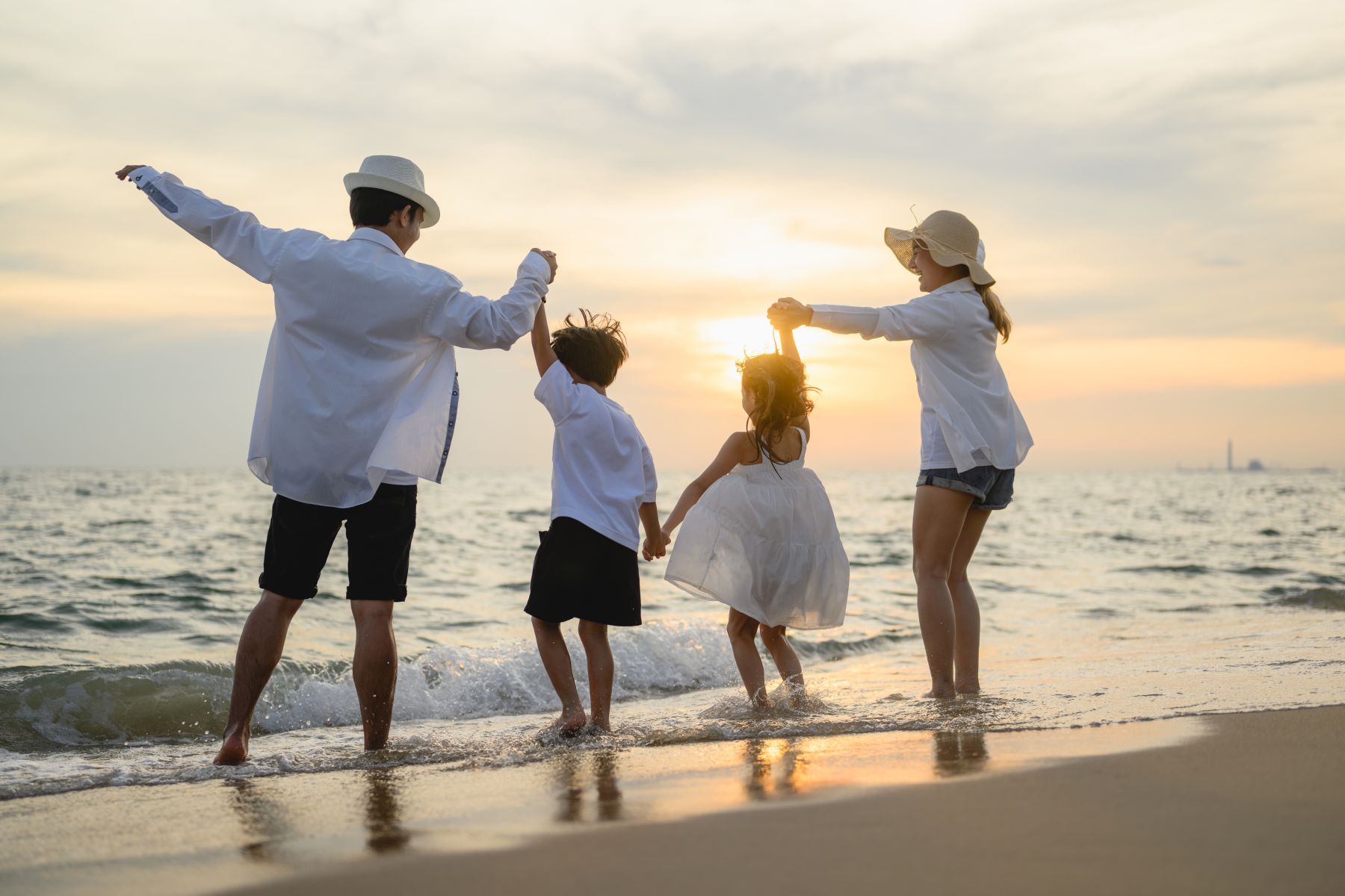 family on beach playing in water at sunset